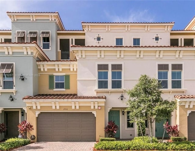 view of front of property with a garage, decorative driveway, a tiled roof, and stucco siding