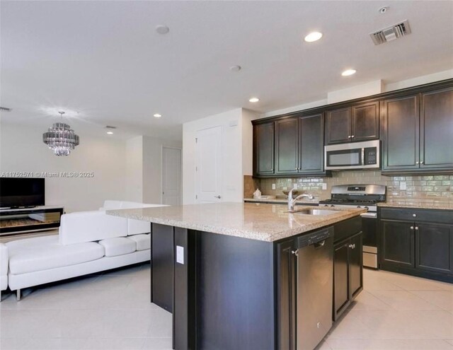 2910 NW 124th Way Unit 2910, Sunrise, FL 33323 - kitchen with appliances with stainless steel finishes, light tile patterned floors, light stone counters, decorative backsplash, and a center island with sink