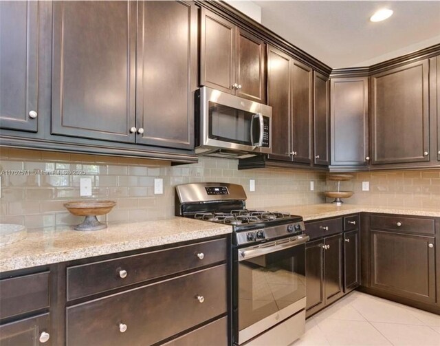 2910 NW 124th Way Unit 2910, Sunrise, FL 33323 - kitchen featuring stainless steel appliances, backsplash, dark brown cabinetry, light stone countertops, and light tile patterned flooring