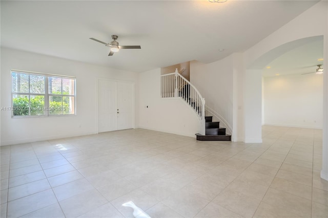 empty room with stairs, ceiling fan, light tile patterned flooring, and baseboards