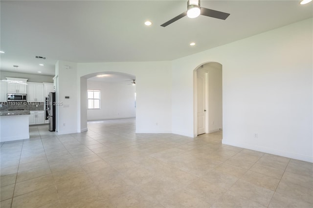 empty room with ceiling fan, arched walkways, baseboards, and recessed lighting