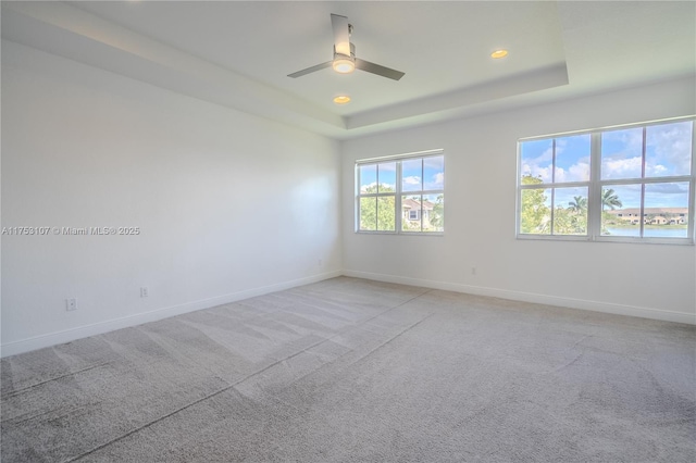 spare room with a tray ceiling, recessed lighting, a ceiling fan, light carpet, and baseboards