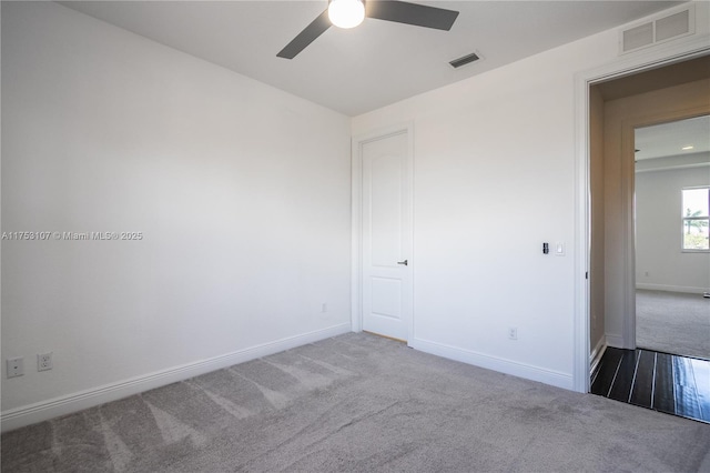 carpeted spare room featuring visible vents, ceiling fan, and baseboards