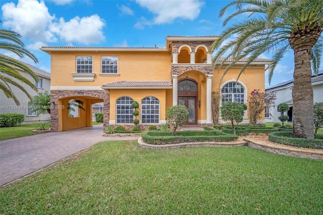 mediterranean / spanish home with decorative driveway, french doors, a tile roof, stucco siding, and a front lawn