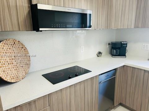 kitchen with black electric cooktop, stainless steel microwave, dishwashing machine, and modern cabinets