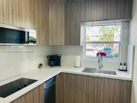 kitchen with stainless steel microwave, modern cabinets, a sink, and black electric cooktop