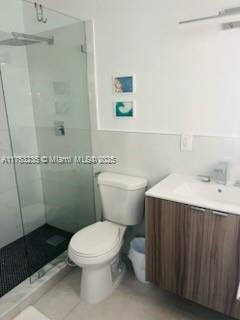 full bathroom featuring vanity, a shower stall, and toilet