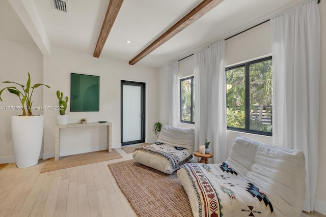 bedroom with beam ceiling, baseboards, visible vents, and light wood finished floors