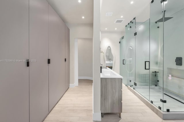 full bathroom with visible vents, wood finished floors, vanity, a shower stall, and recessed lighting