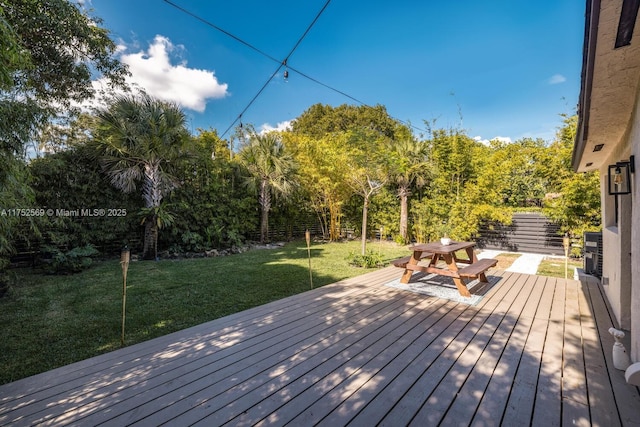 deck featuring outdoor dining space, a lawn, and fence