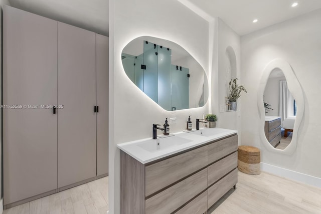 bathroom with double vanity, recessed lighting, a sink, and wood finished floors