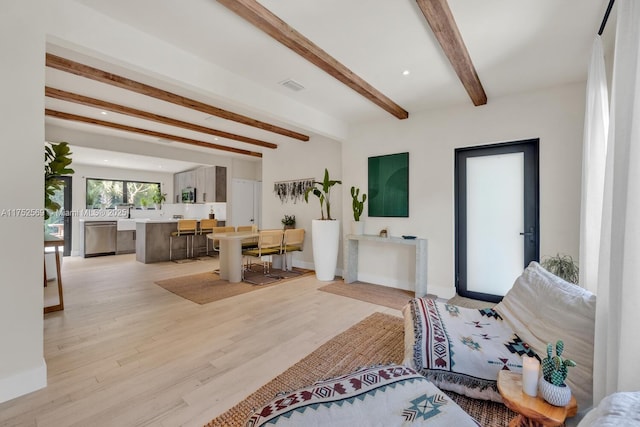 living room with beam ceiling, light wood finished floors, recessed lighting, visible vents, and baseboards