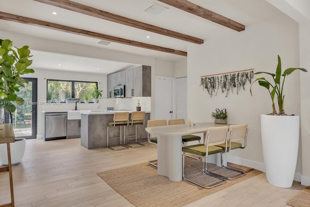 dining space featuring visible vents, beamed ceiling, light wood-style flooring, and baseboards