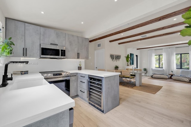 kitchen featuring stainless steel appliances, gray cabinets, a sink, beverage cooler, and a peninsula