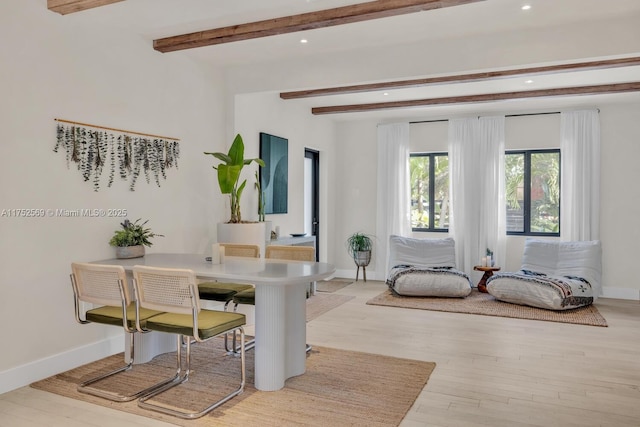 dining space featuring light wood-type flooring, beam ceiling, and baseboards