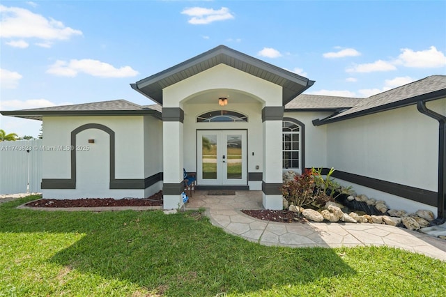 doorway to property featuring stucco siding, roof with shingles, a lawn, and french doors