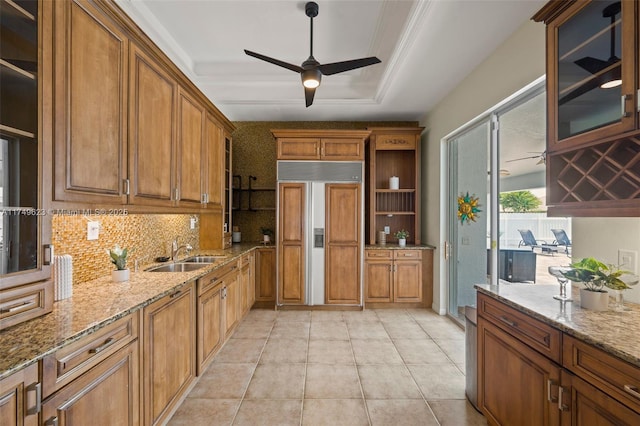 kitchen featuring open shelves, brown cabinetry, ceiling fan, a sink, and paneled refrigerator