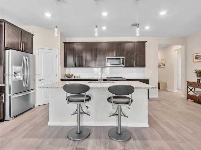 kitchen featuring stainless steel appliances, visible vents, a sink, and light wood-style flooring