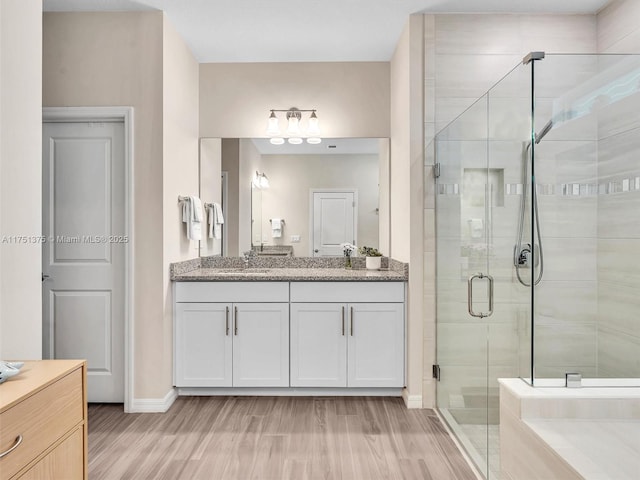 bathroom with a shower stall, baseboards, wood finished floors, and vanity