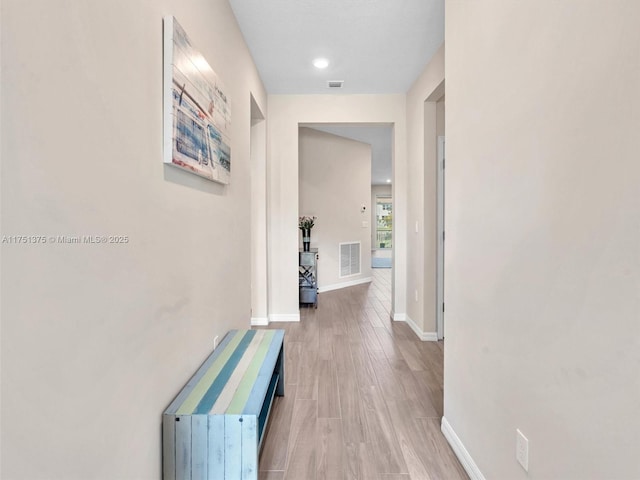 hallway featuring wood finished floors, visible vents, and baseboards