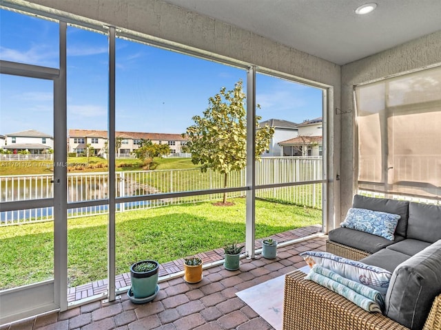 unfurnished sunroom featuring a water view, a residential view, and a wealth of natural light