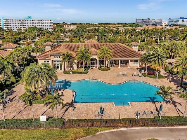 community pool with a patio area, fence, and a city view