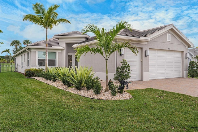 view of side of home featuring decorative driveway, stucco siding, a lawn, an attached garage, and fence