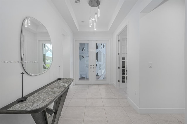 entrance foyer with light tile patterned floors, baseboards, a tray ceiling, and french doors