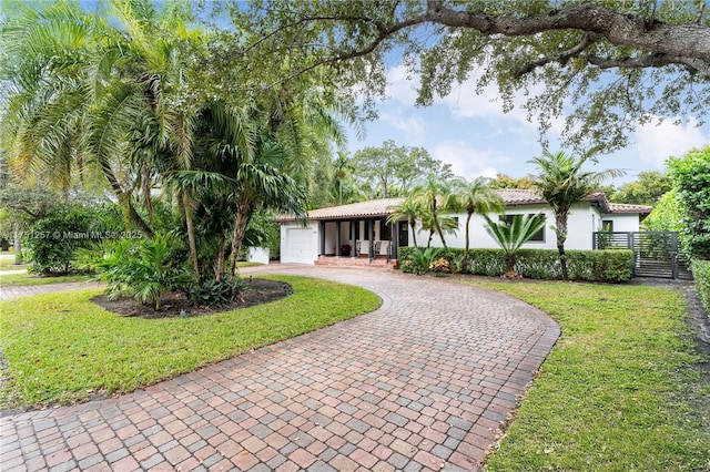 view of front facade featuring a garage, fence, decorative driveway, a front lawn, and stucco siding