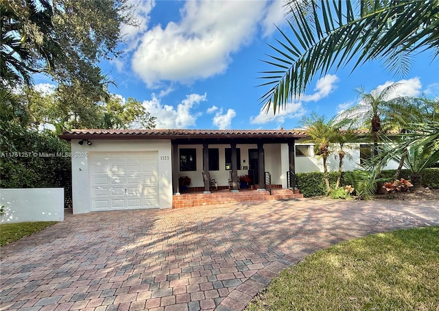 view of front of home with a garage, a tiled roof, decorative driveway, and stucco siding