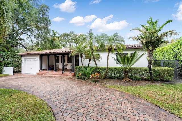 view of front facade with a garage, fence, decorative driveway, a porch, and stucco siding