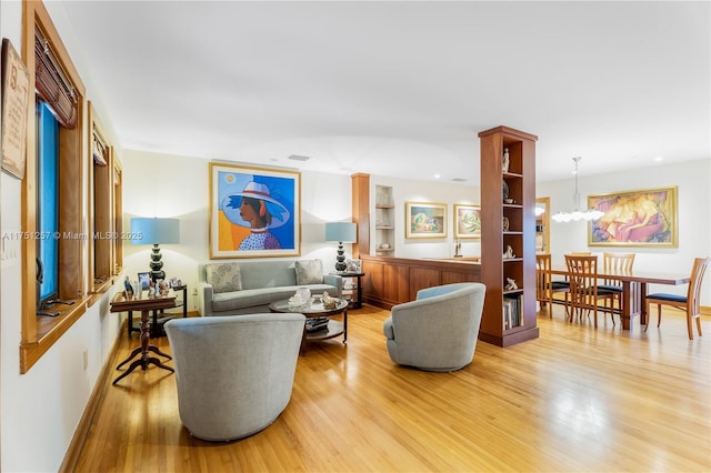 living room featuring light wood-type flooring and a notable chandelier