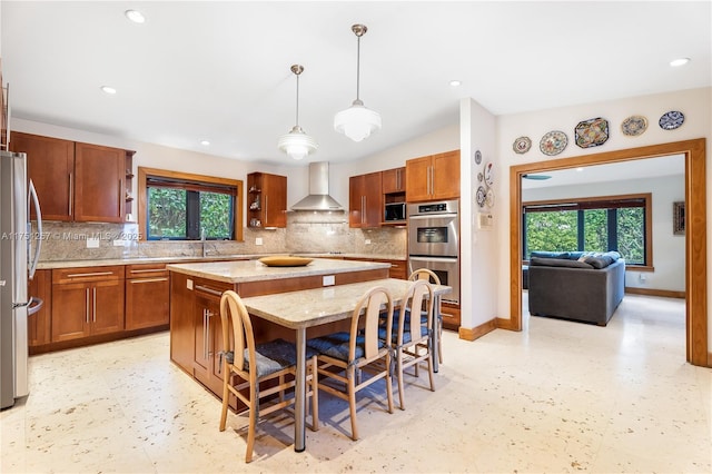 kitchen with wall chimney exhaust hood, light floors, a center island, and stainless steel appliances