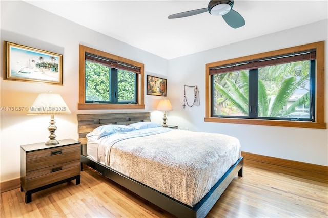 bedroom with light wood-style flooring, multiple windows, baseboards, and ceiling fan