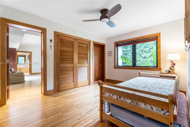 bedroom with a closet, light wood-type flooring, a ceiling fan, and baseboards