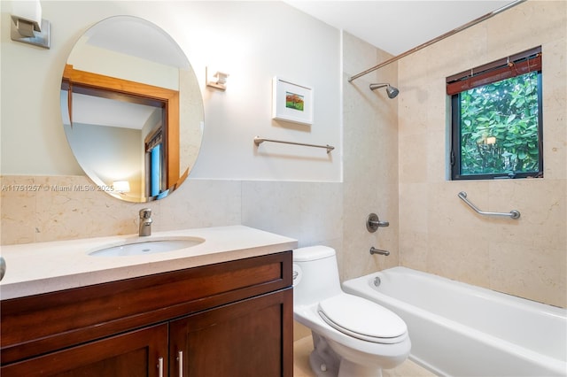 bathroom featuring toilet, vanity, tile walls, shower / washtub combination, and wainscoting