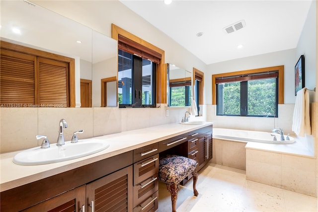 bathroom with a bath, double vanity, visible vents, and a sink