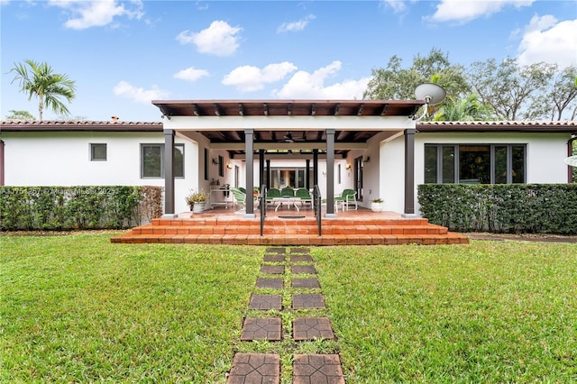 back of property with a patio, a lawn, and stucco siding