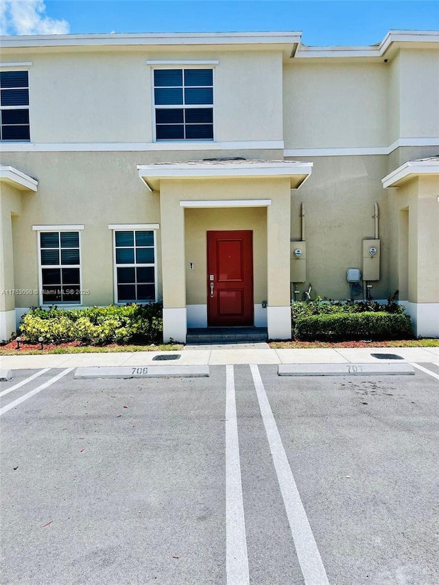 doorway to property featuring uncovered parking and stucco siding