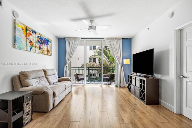 living room with a textured ceiling, light wood finished floors, a ceiling fan, and floor to ceiling windows