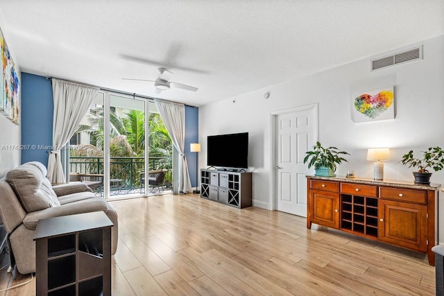 living area with light wood-style flooring, floor to ceiling windows, visible vents, and ceiling fan