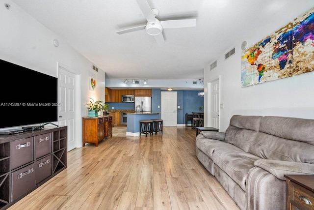 living room with light wood-type flooring, ceiling fan, and visible vents