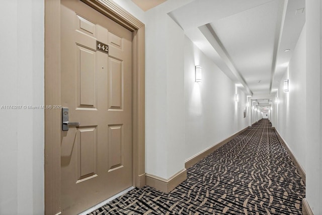 hall featuring carpet and baseboards