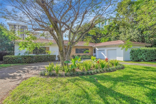 view of front of property featuring aphalt driveway, an attached garage, a front lawn, and stucco siding