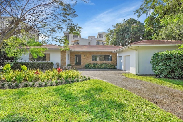 view of front of home with a garage, an outdoor structure, driveway, stucco siding, and a front lawn