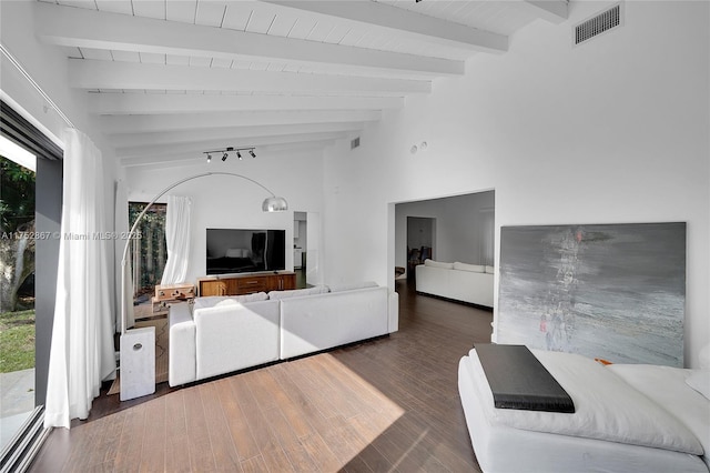 unfurnished living room featuring a healthy amount of sunlight, beam ceiling, visible vents, and wood finished floors