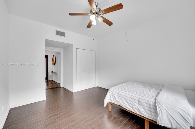 bedroom with a closet, visible vents, a ceiling fan, wood finished floors, and baseboards