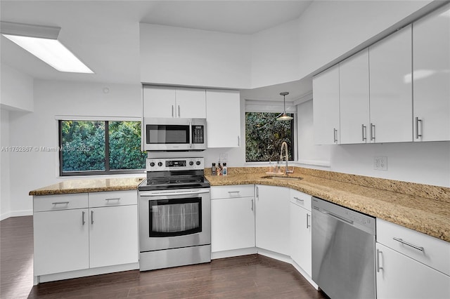 kitchen with dark wood-style floors, appliances with stainless steel finishes, white cabinets, and a sink