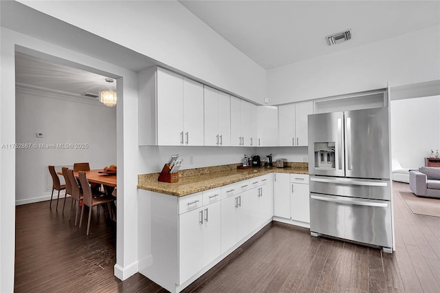 kitchen featuring light stone countertops, visible vents, dark wood-type flooring, and stainless steel fridge with ice dispenser