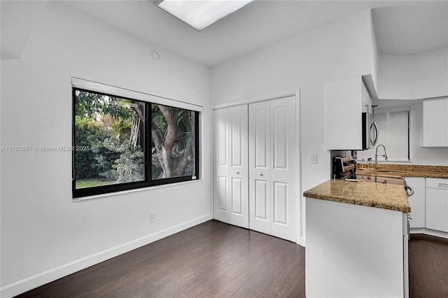 kitchen featuring white cabinets, stainless steel microwave, baseboards, and dark wood-style flooring